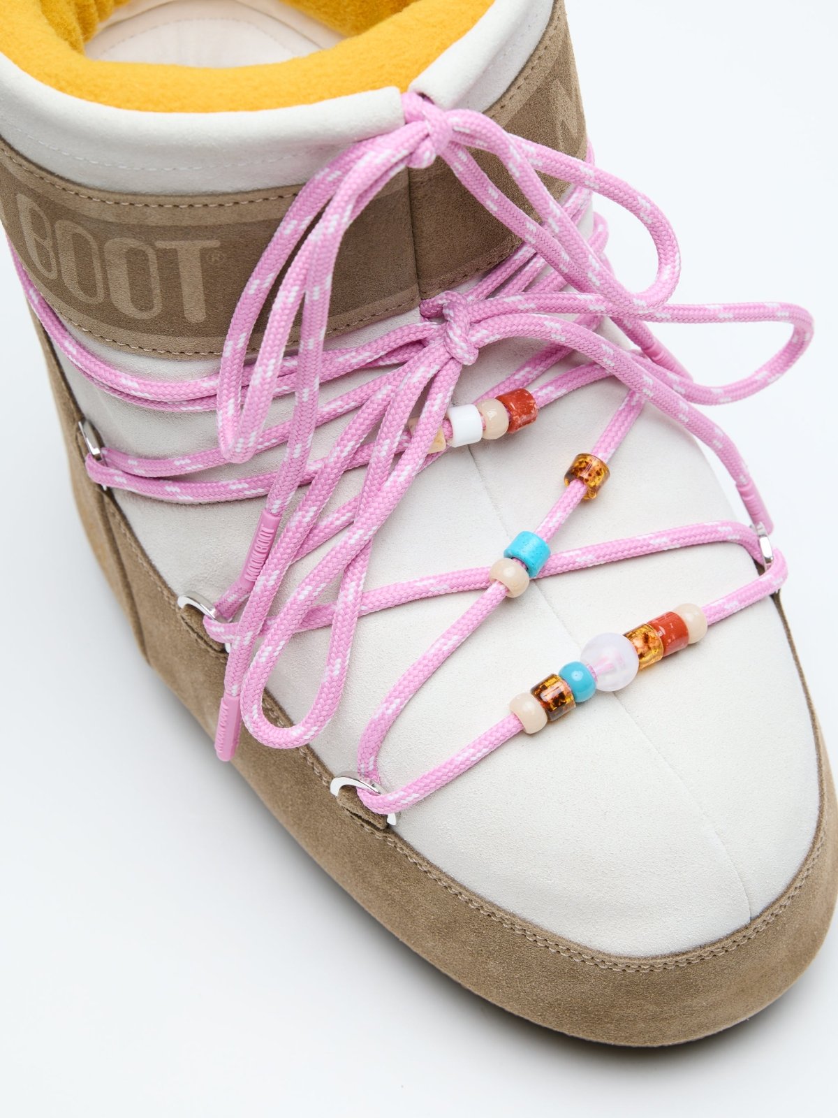 Close-up of MB X GIR ICON LOW SUEDE BEADS sneaker with pink laces and colorful bead details on beige suede and white fabric.