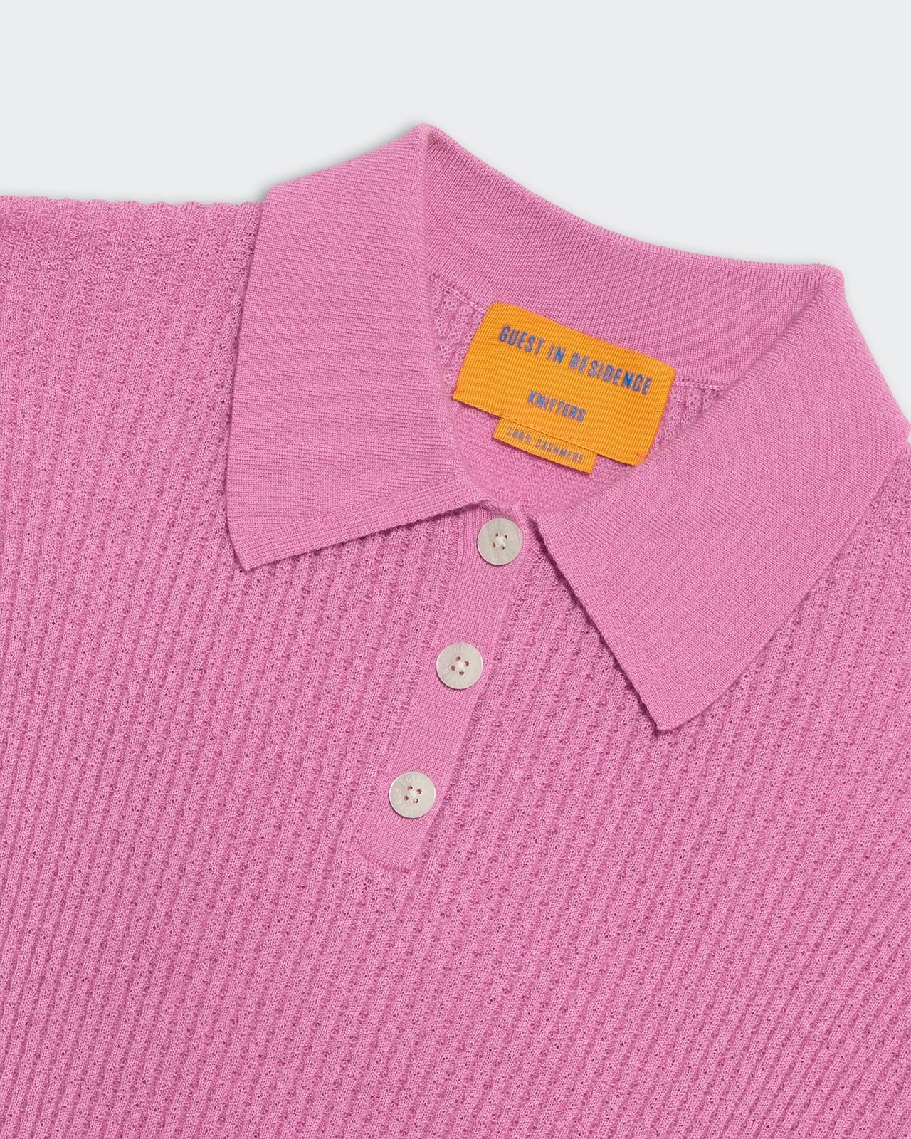Close-up of a rose pink lightweight waffle knit polo shirt with three-button placket and soft collar detail