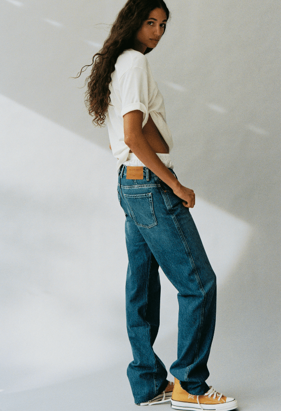 WEEKENDER fashion look featuring a model in a white cropped top blue wide leg jeans and classic canvas sneakers against a softly lit studio wall