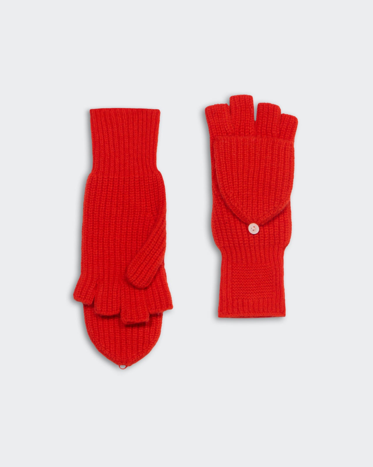 Pair of bright red knit fingerless mitts with convertible flap laid flat on a light background