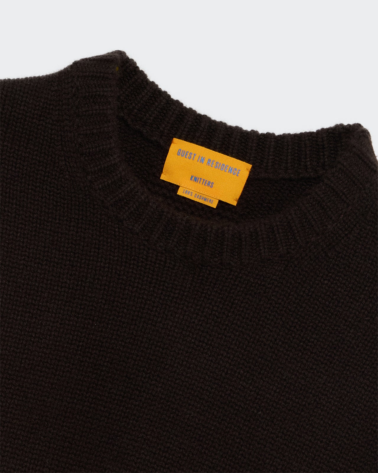 Close-up of the Cozy Crew - Burnt Cocoa sweater neckline with textured knit and orange label inside collar.