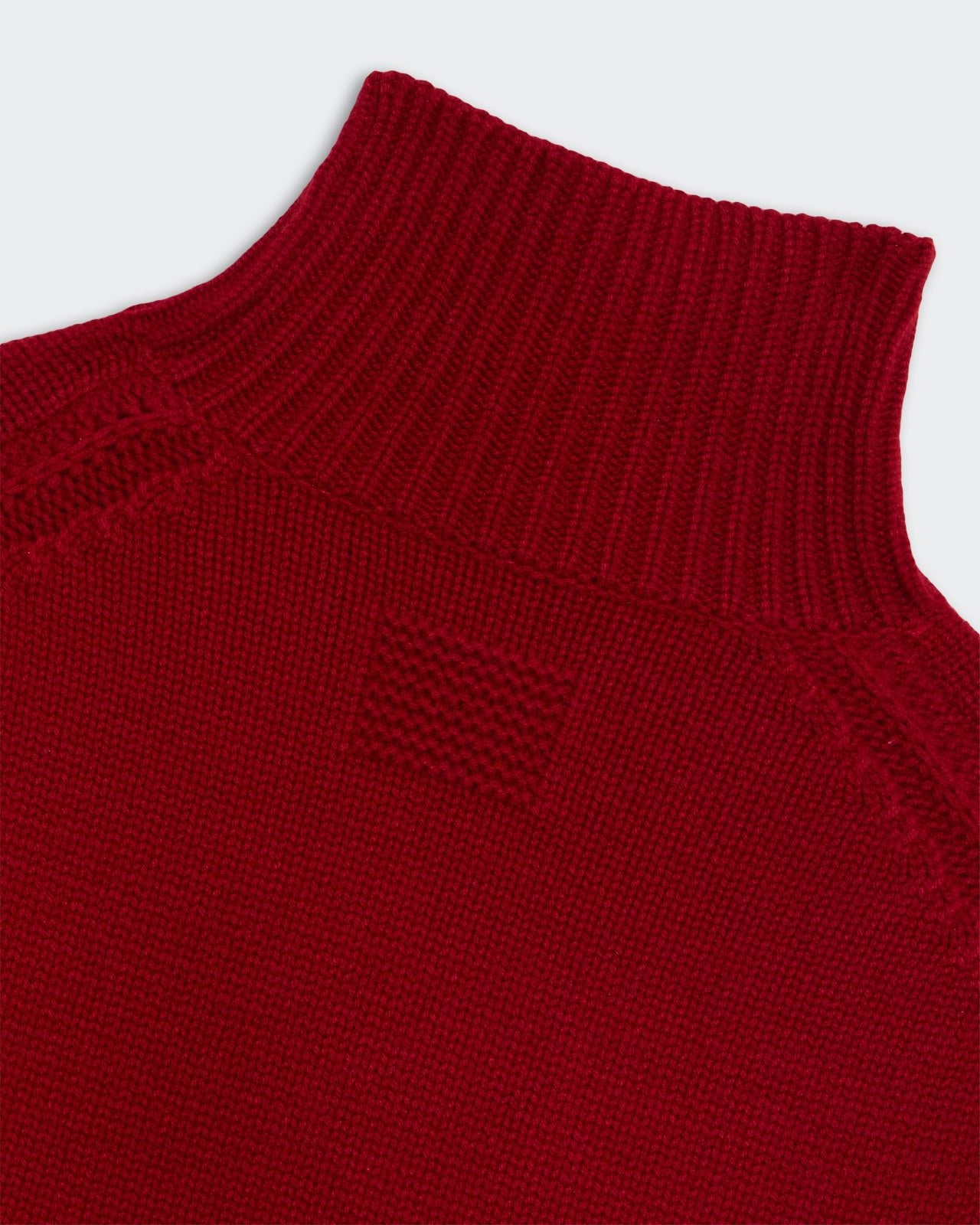 Close-up of red knit turtleneck sweater showing ribbed collar and Cozy Turtleneck Ruby fabric texture detail.