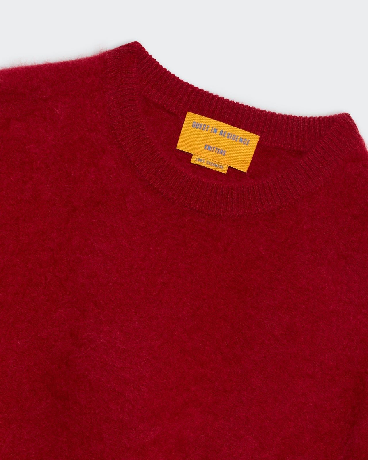 Grizzly Crew - Ruby red knitted crew neck sweater with a soft fuzzy texture and yellow brand label inside collar.