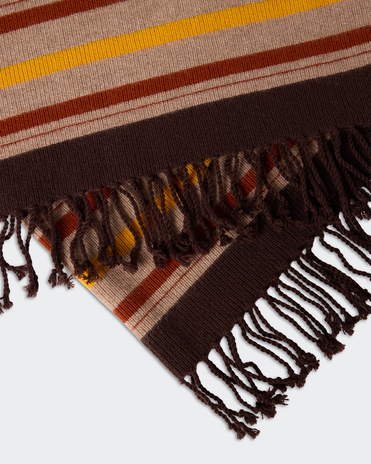 Close-up of the Striped Blanket - Burnt Cocoa Combo with woven fringes and warm brown, burnt orange, and mustard yellow stripes on a beige background