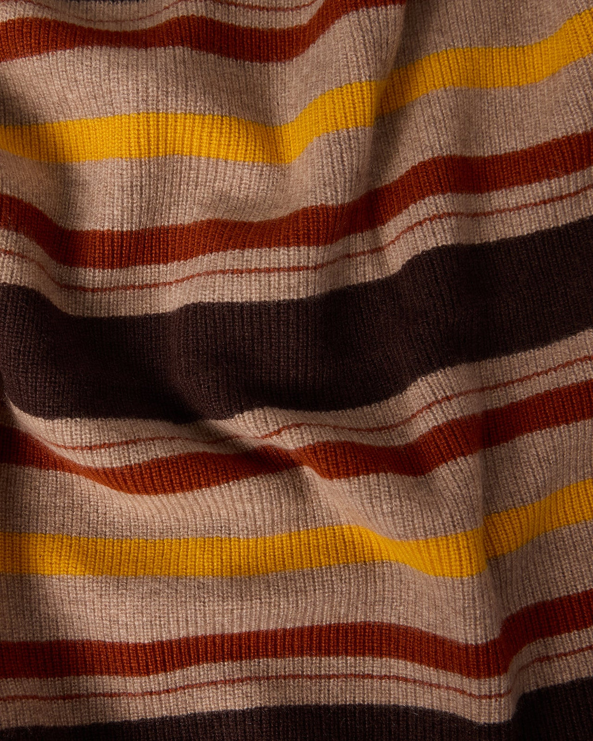 Close-up of a textured fabric with warm burnt cocoa, orange, yellow, and beige stripes in the Striped Blanket - Burnt Cocoa Combo pattern