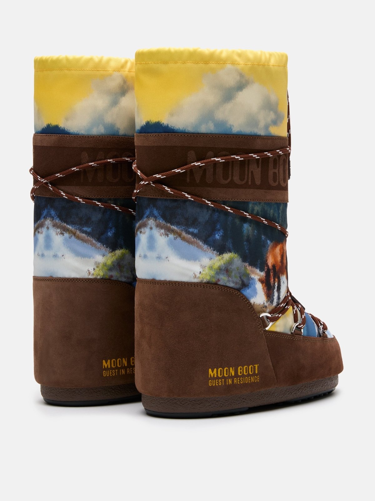 Pair of Moon Boot winter boots with mountain and sky print and yellow top detail