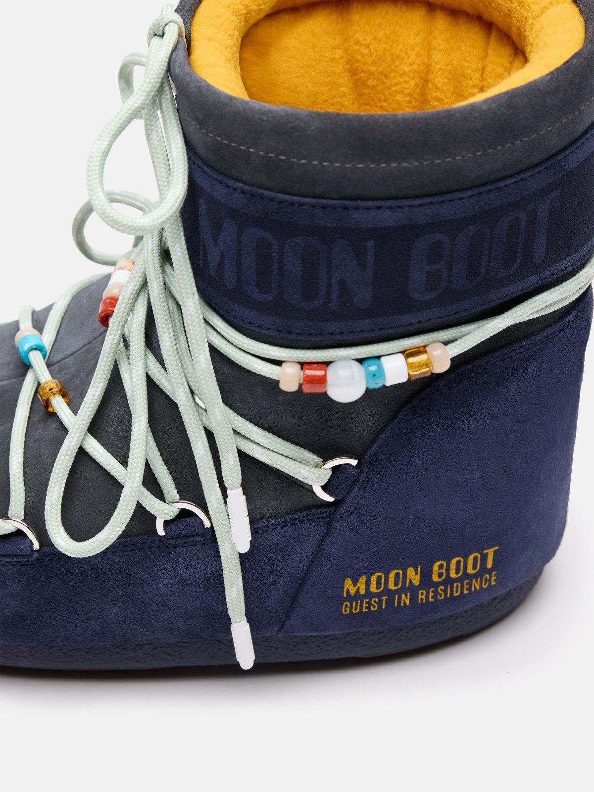 Close-up of navy blue MB X GIR Icon low suede boot with colorful beads on light green laces and yellow interior lining