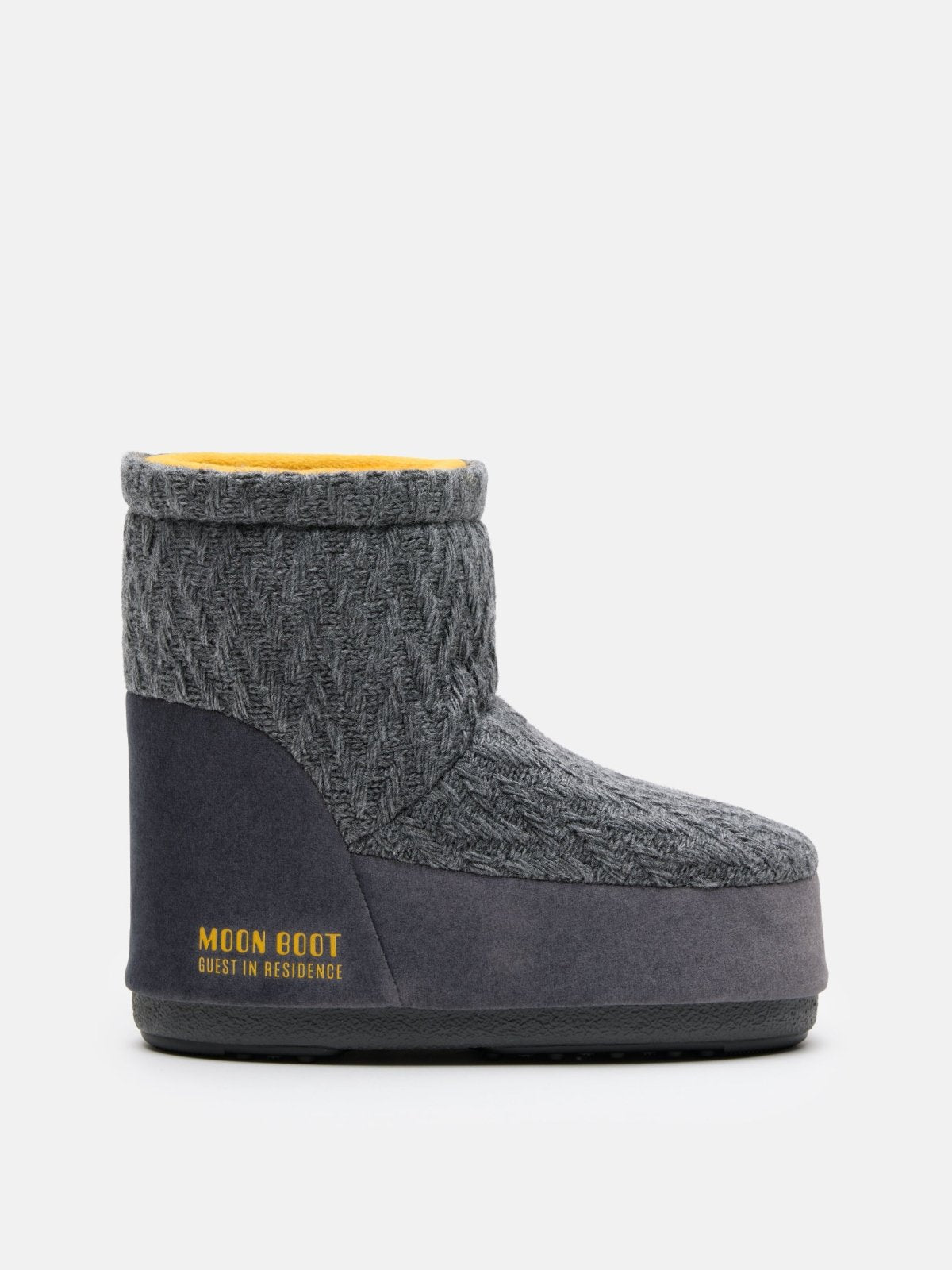 Grey knit Moon Boot slipper with thick sole and yellow interior lining sitting on white background