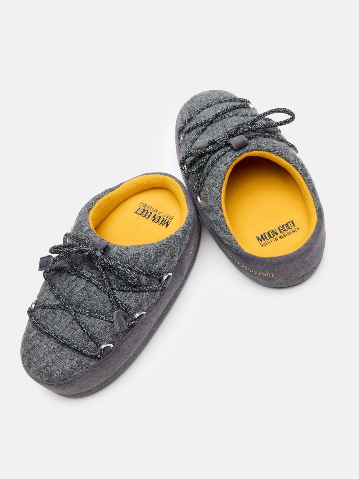 Pair of gray knit mule slippers with yellow insoles and black laces designed for comfort and warmth