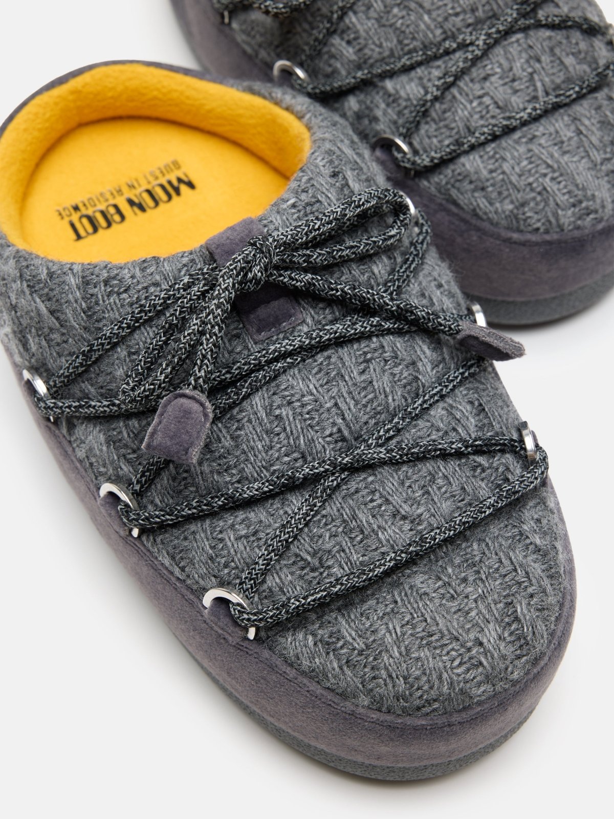 Close-up of gray knit MB X GIR EVX Mule with black laces and soft yellow inner sole on a white background