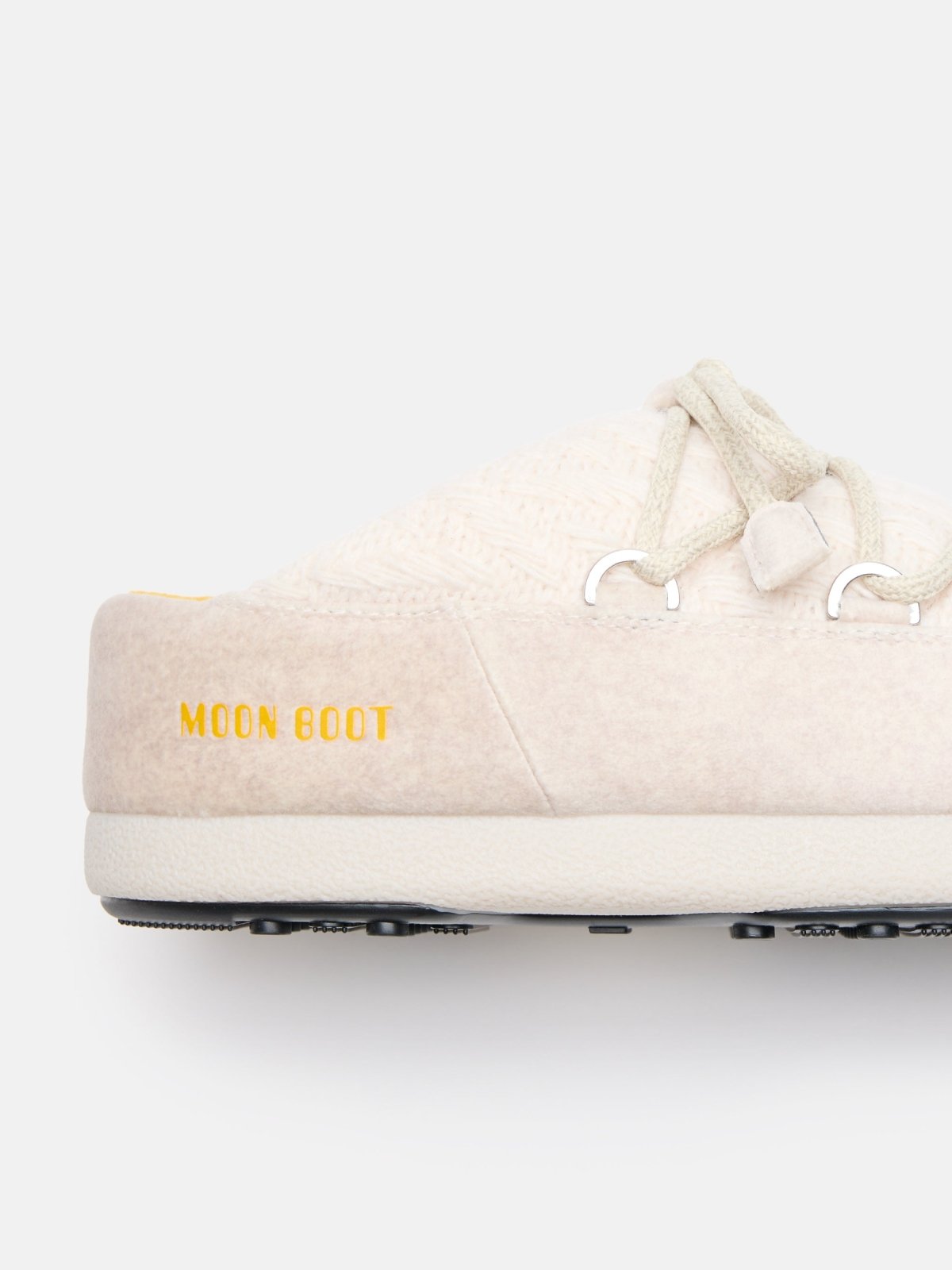 Close-up side view of beige MB X GIR EVX MULE KNIT slipper with yellow Moon Boot logo and knit upper details.