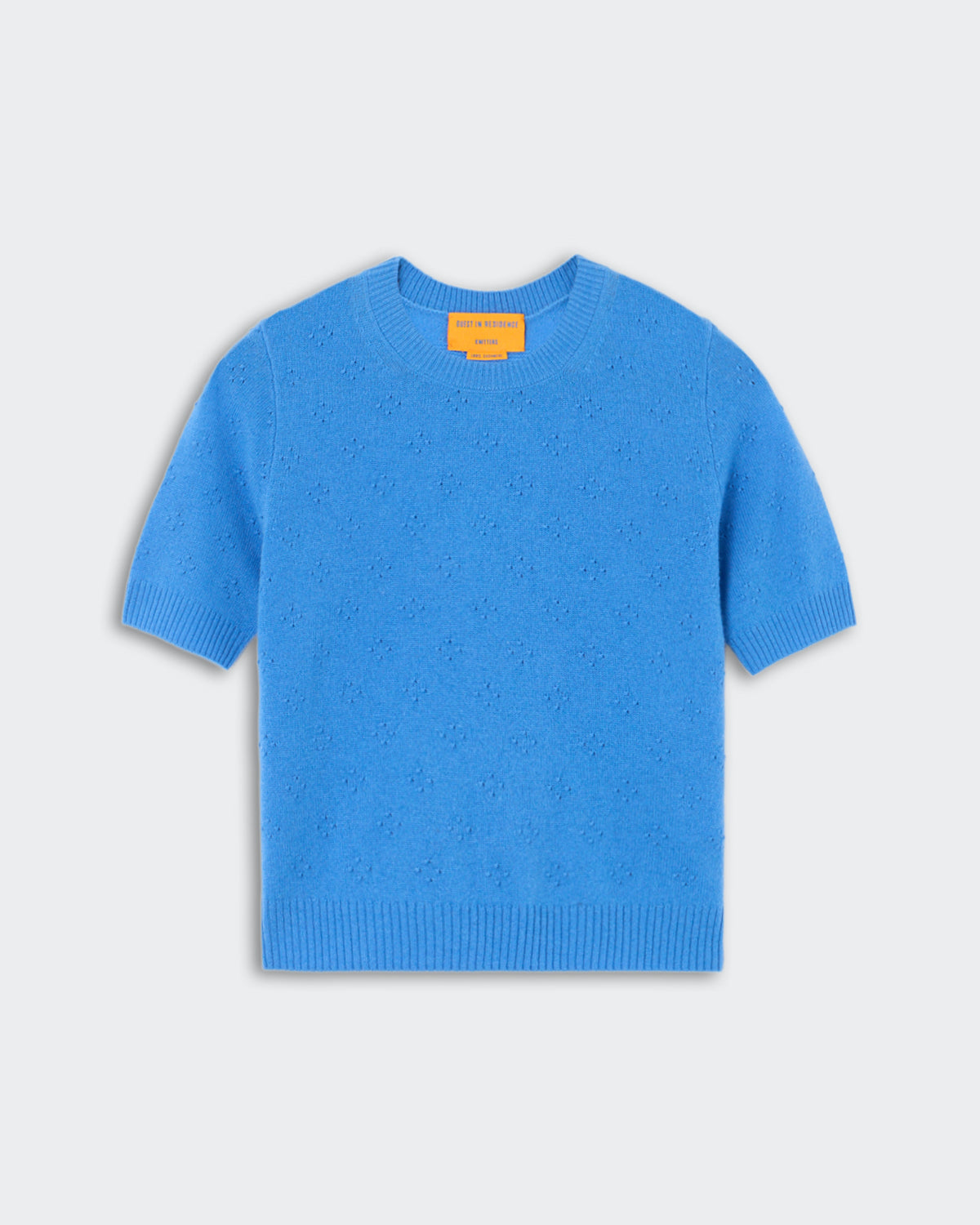 Compass Sweater Tee - Sail, a bright blue short-sleeve knit sweater with subtle textured floral details, featuring a crew neckline and ribbed cuffs and hem, displayed flat.
