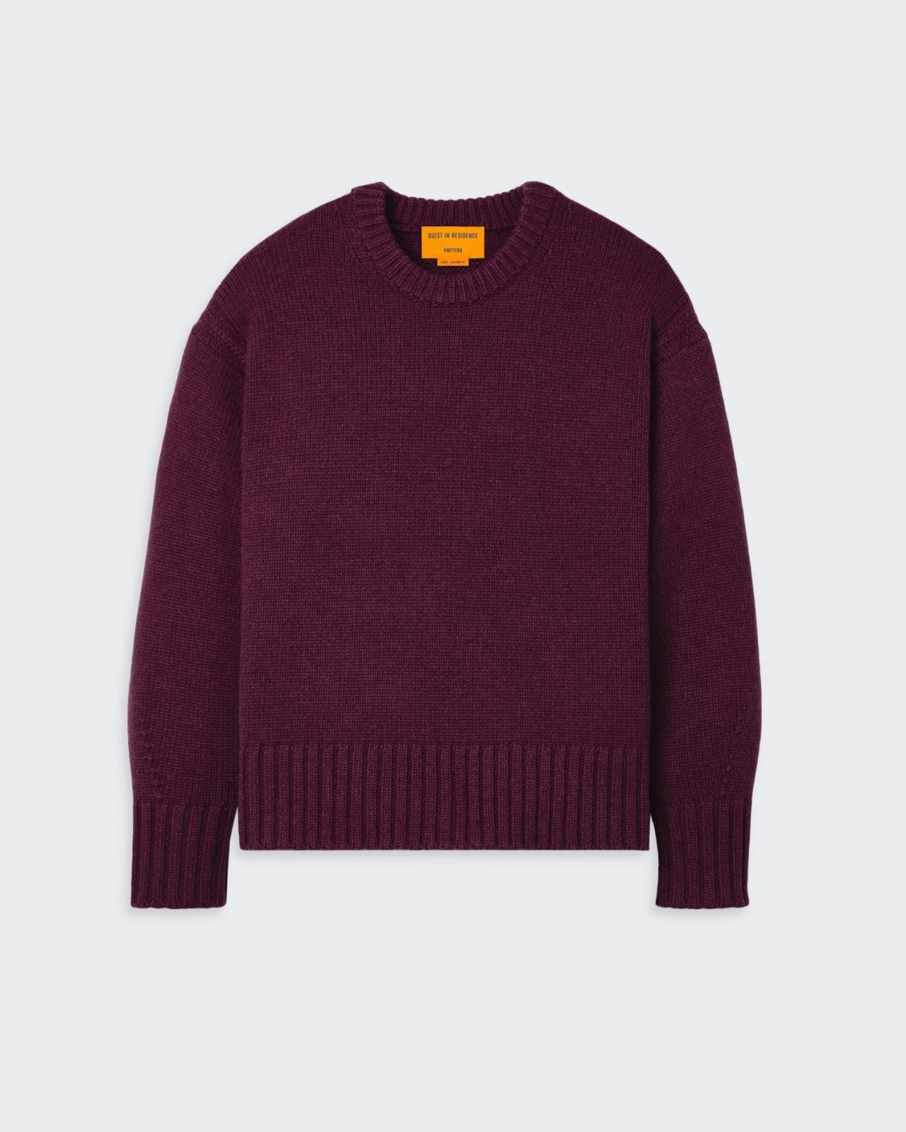 A cozy, oversized women's plum-colored crew neck sweater with dropped shoulders, reverse jersey detailing, and ribbed cuffs and hem.