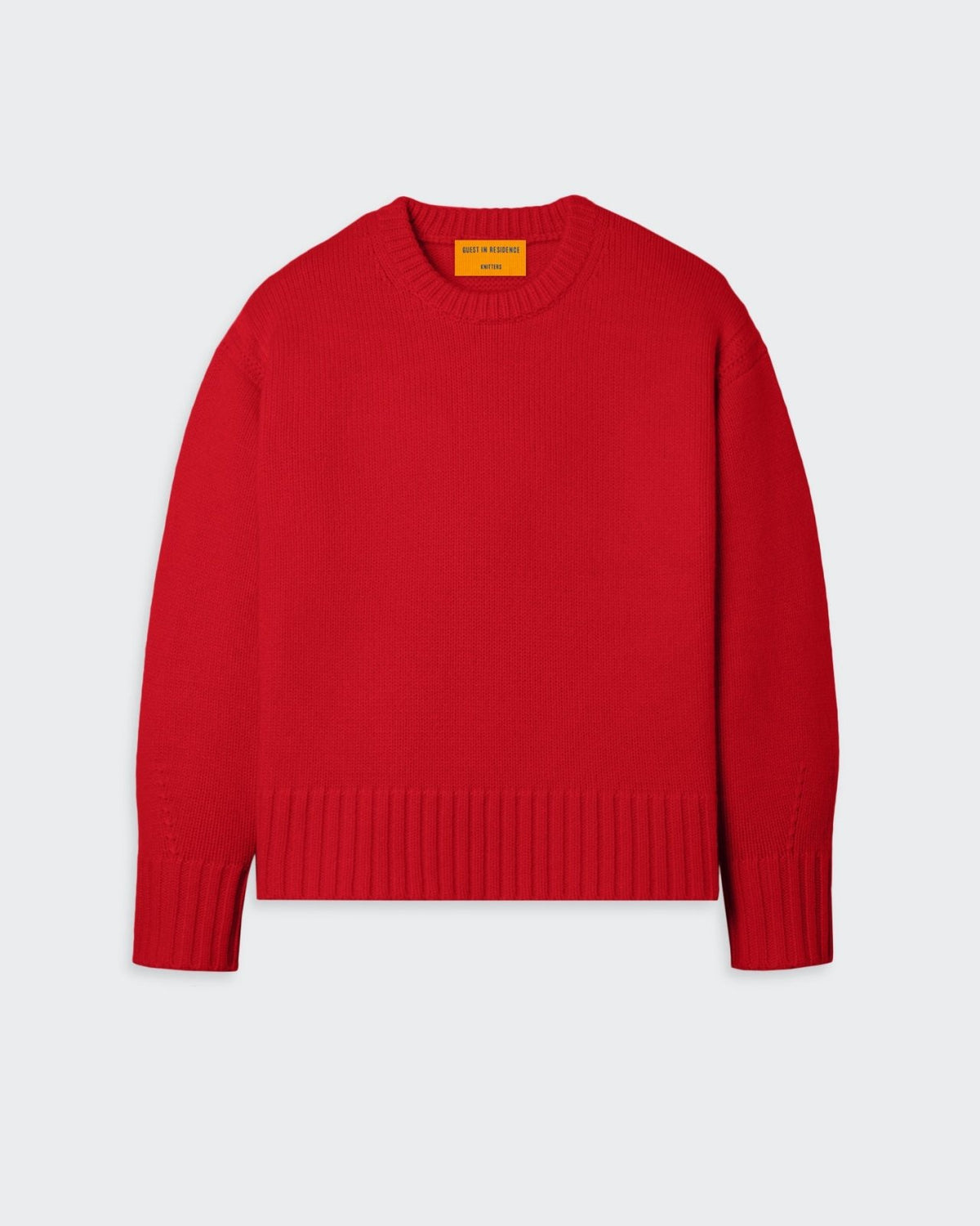 A cozy red sweater with a crew neck and dropped shoulders, featuring a reverse jersey detail on the arms and shoulders with a tuck stitch, ribbed neck trim, cuffs, and hem, and a side slit at the hem. The sweater is made of 100% premium cashmere from Inner Mongolia, with a heavy-weight knit construction.