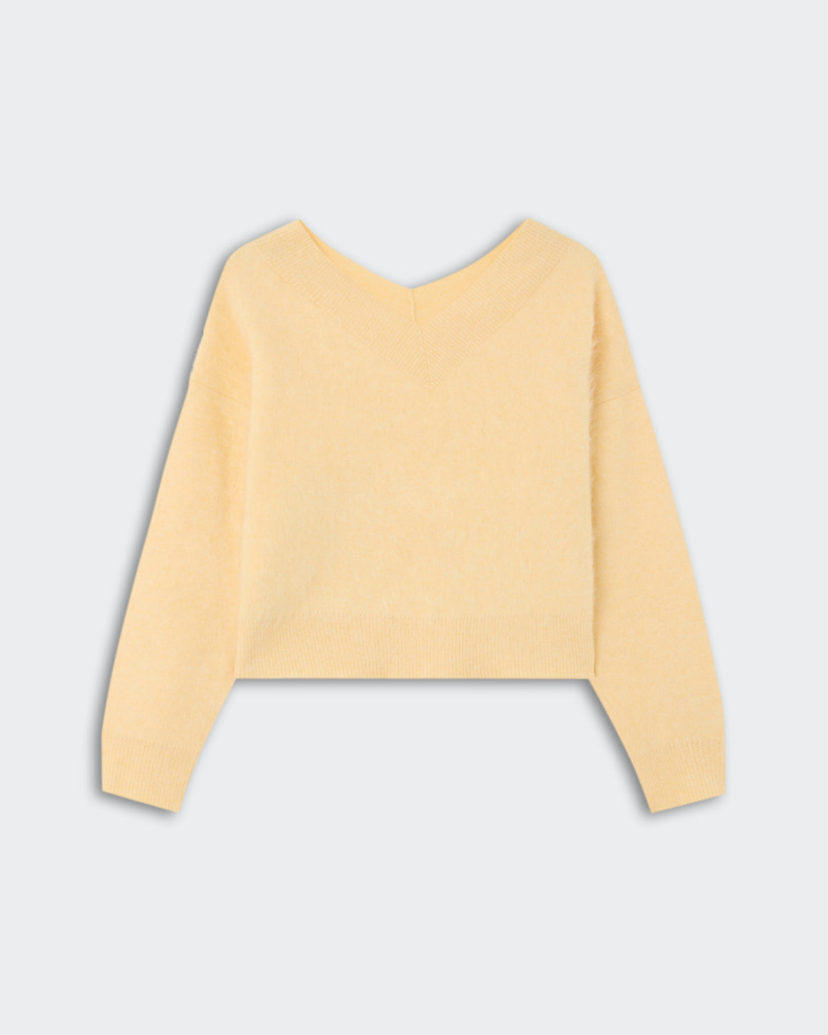 Soft light yellow sweater with a V-neck and long sleeves made from cashmere fabric, named Grizzly Double V - Butter, laid flat on a light background.