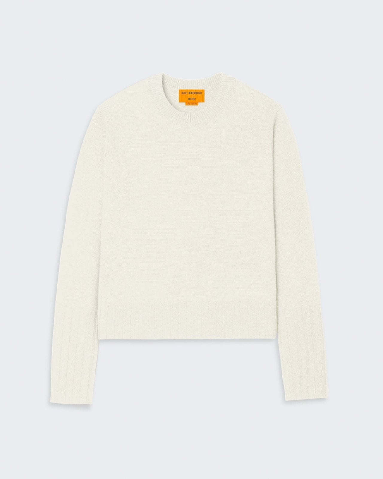 A cream-colored women's cashmere sweater with a shrunken, slim fit and high ribbed cuffs and hem.