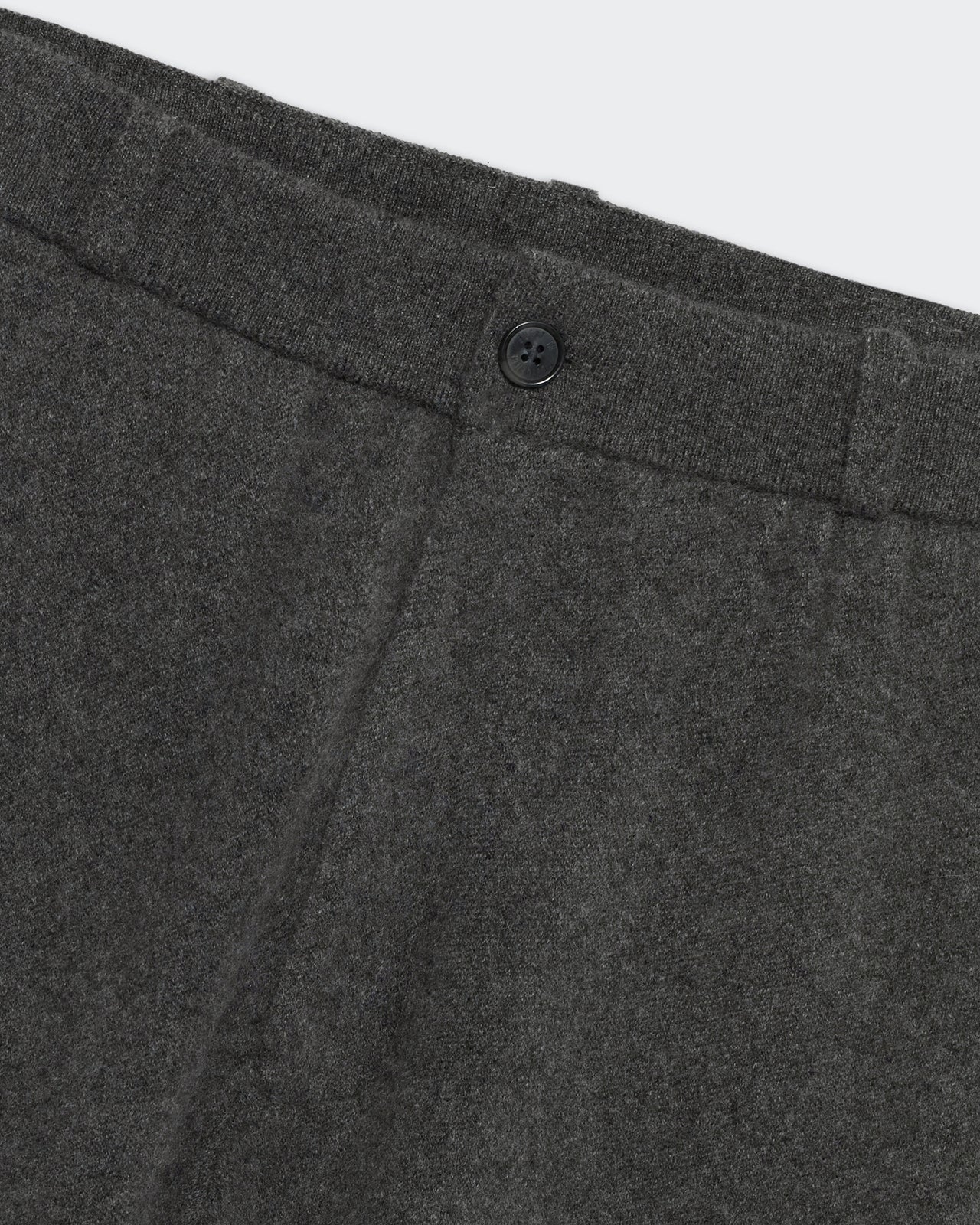 Close-up of tailored trouser charcoal fabric with button and waistband stitching details.