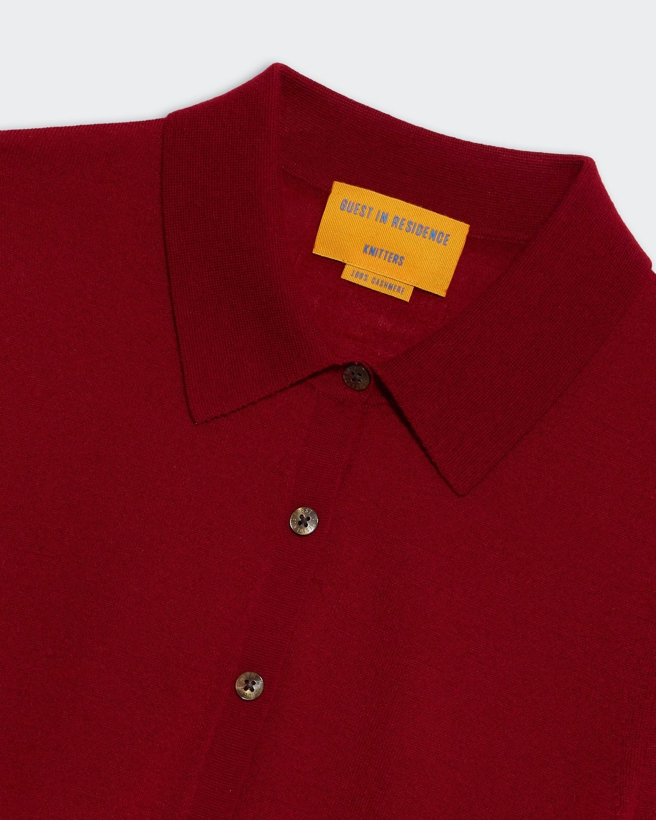 Elle Shirt in Cashmere Ruby showing close-up of deep red fabric, collar, and buttons on a light background