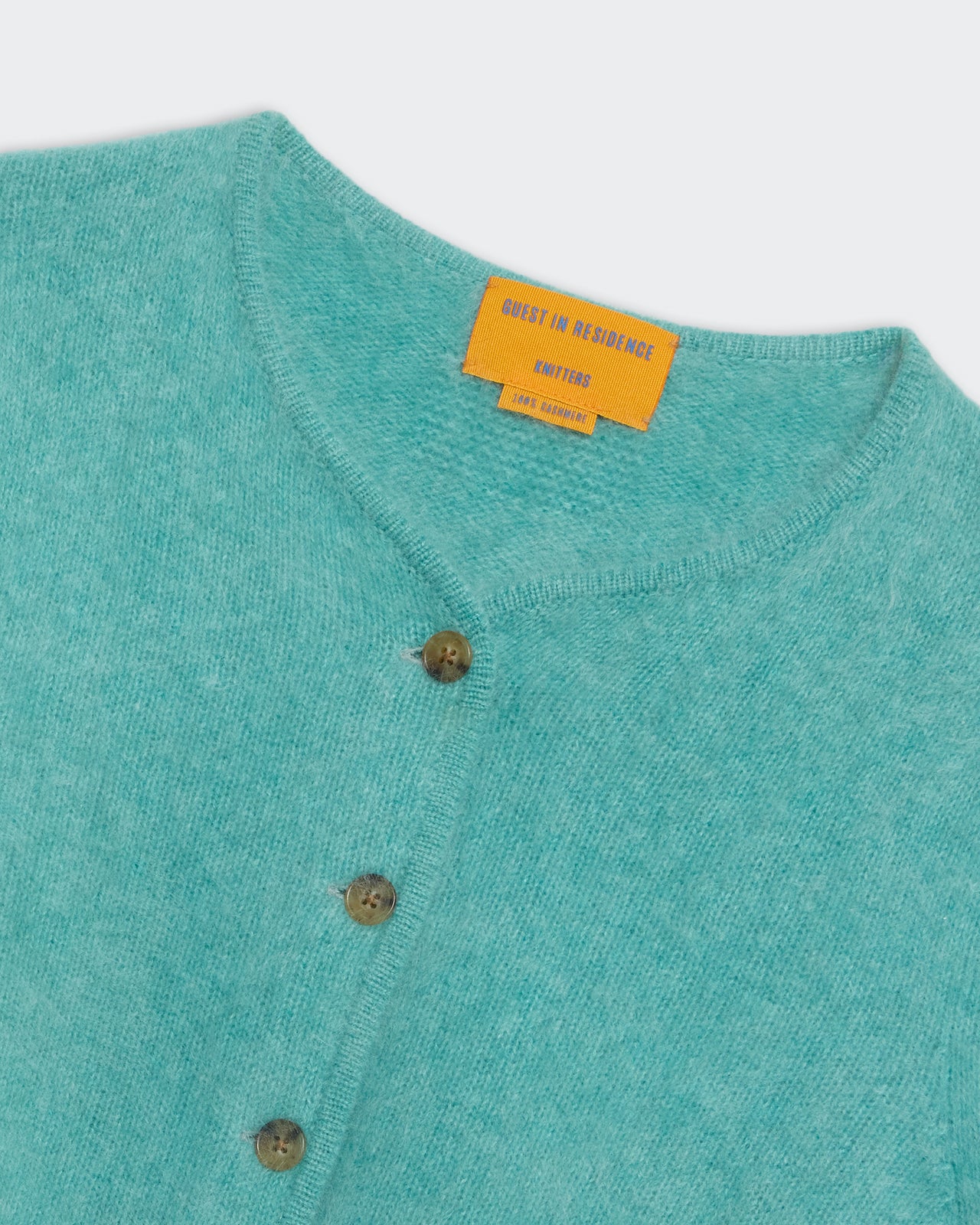 Grizzly Cardigan - Glacier in soft teal knit with brown buttons and orange label, cozy and stylish winterwear.