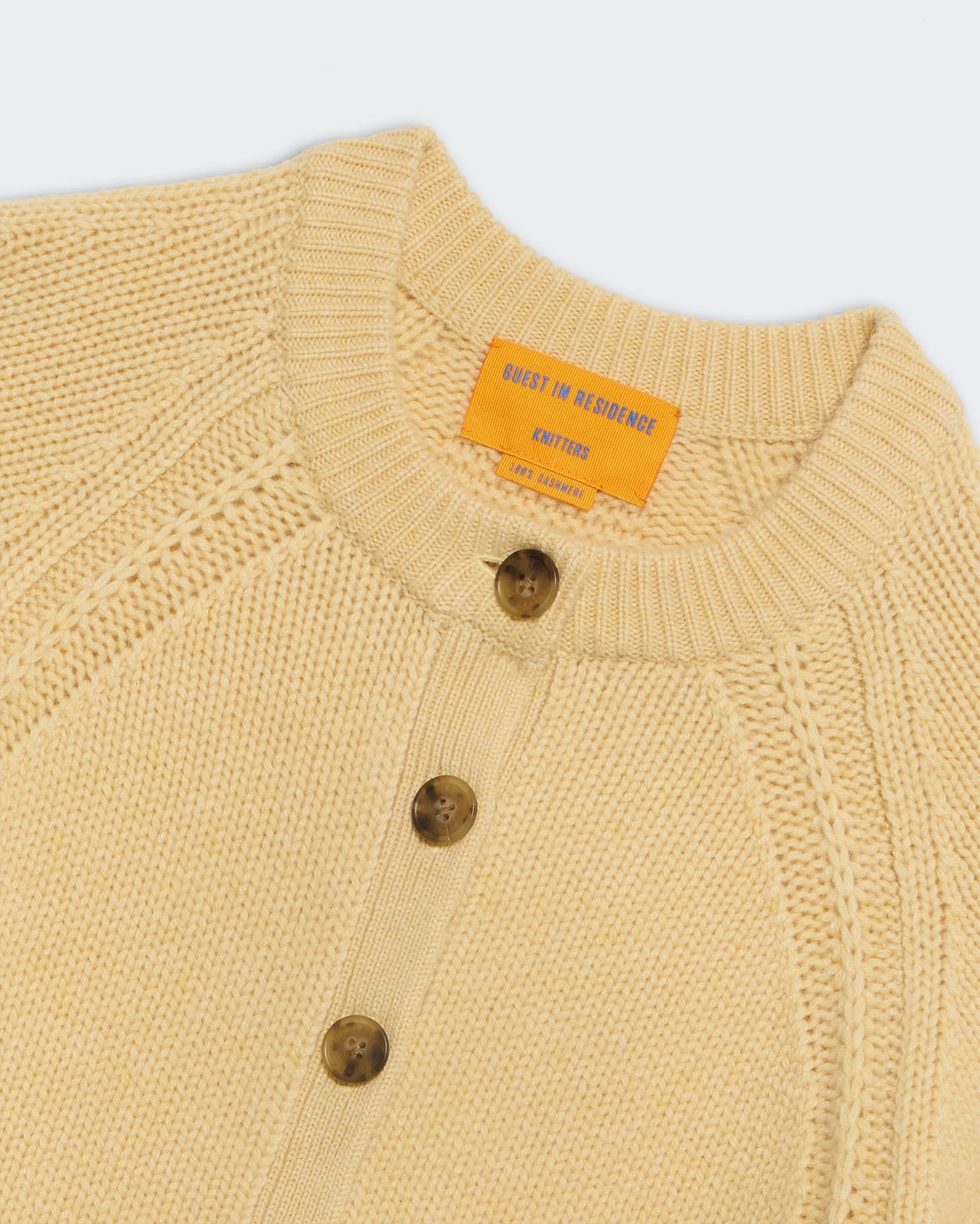 Sculpted Cardigan - Butter close-up of yellow cashmere knit with button closure and raglan-style sleeves.