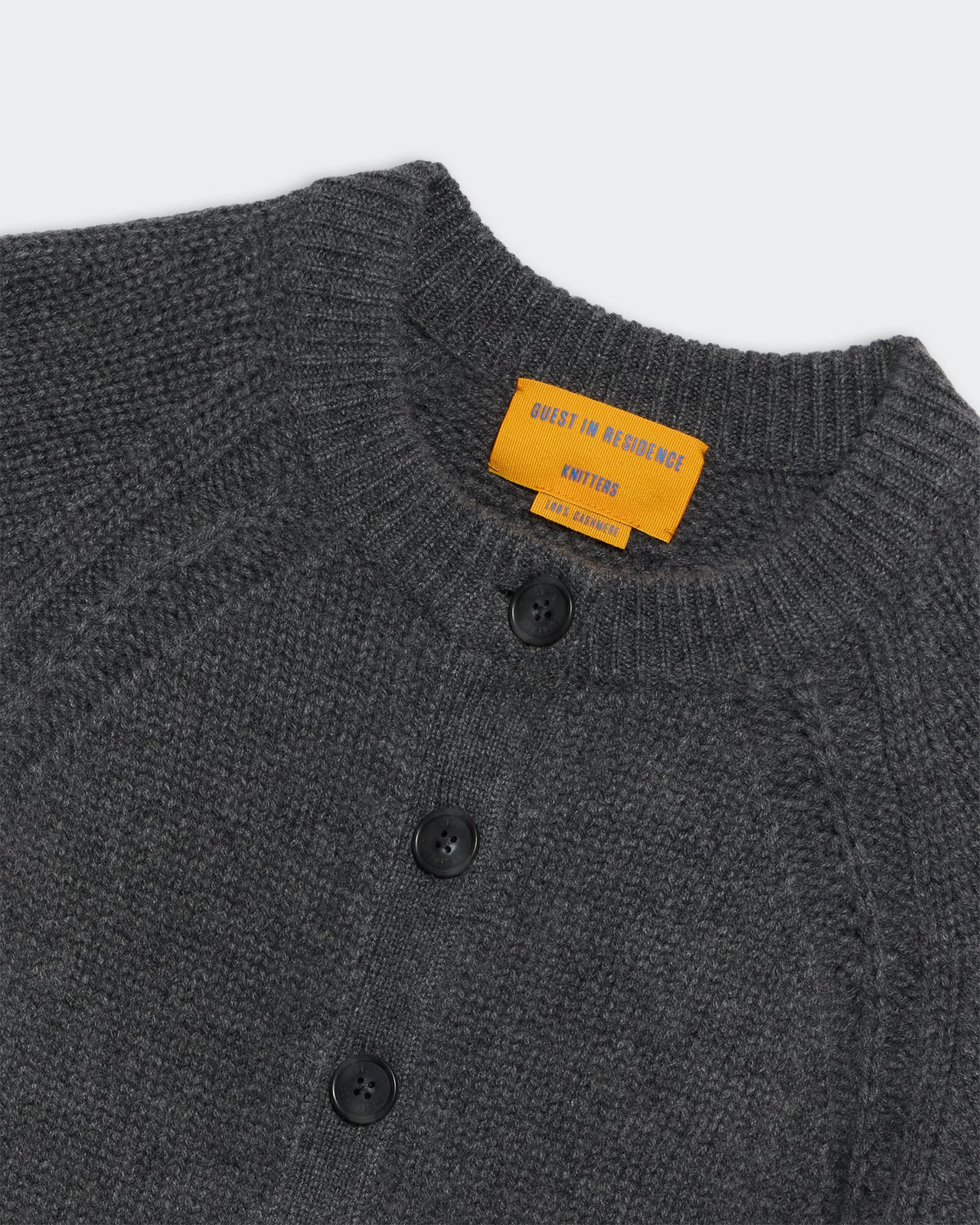 Close-up of the charcoal Sculpted Cardigan showing knit texture, front button closure, and ribbed collar.