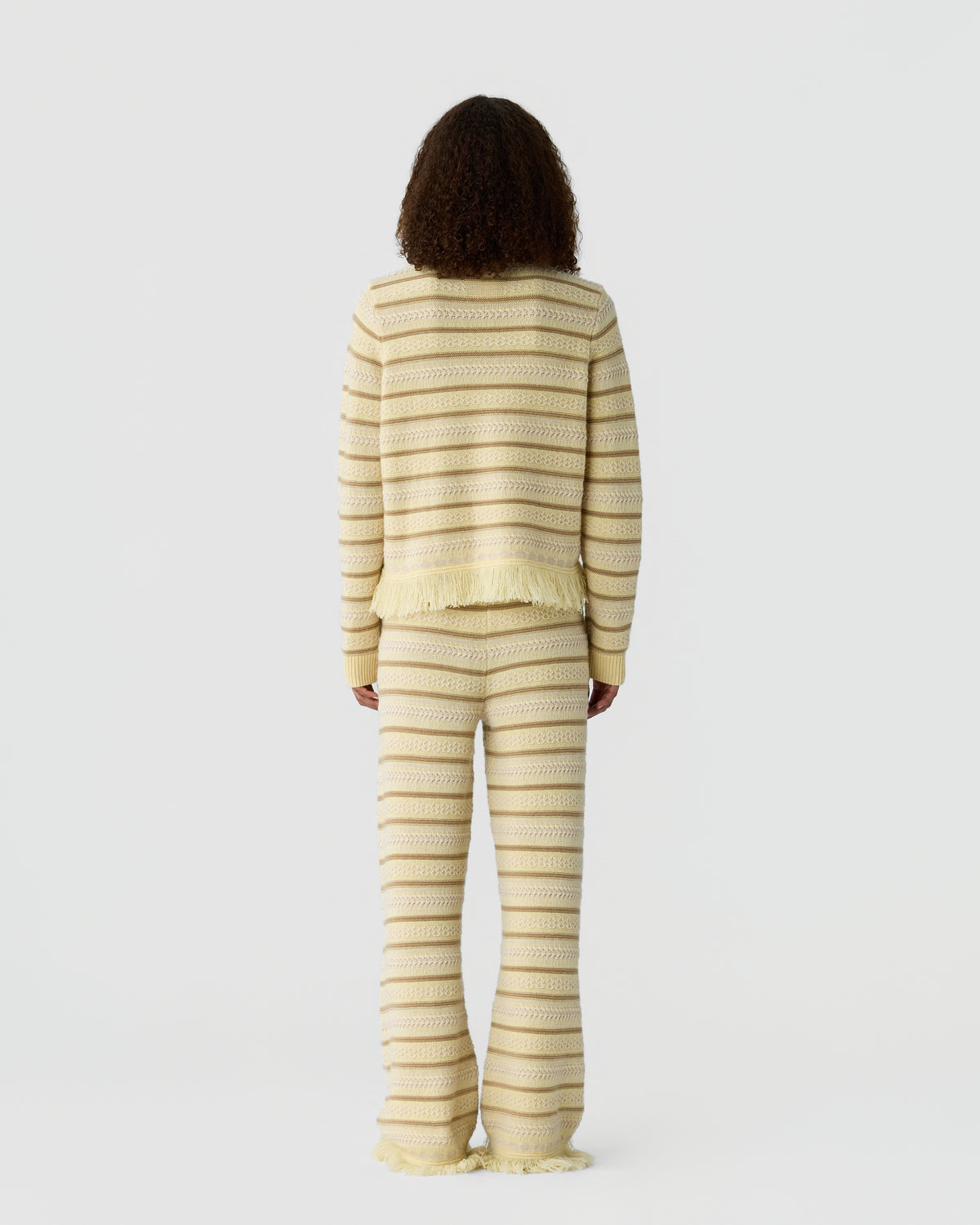 Person viewed from behind wearing a cream striped knit sweater and matching wide leg pants against a plain light background