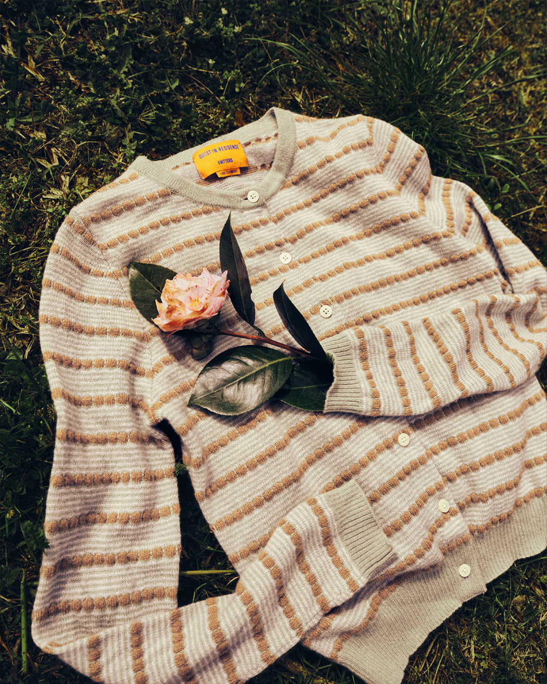 Pebble Stripe Jane Cardigan in Sage Brush Combo laid on grass with a flower